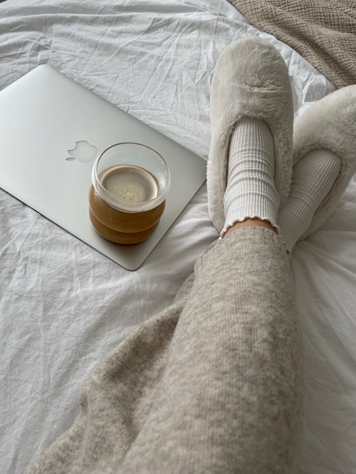Comfortable moment at home with a laptop, coffee, and warm slippers.