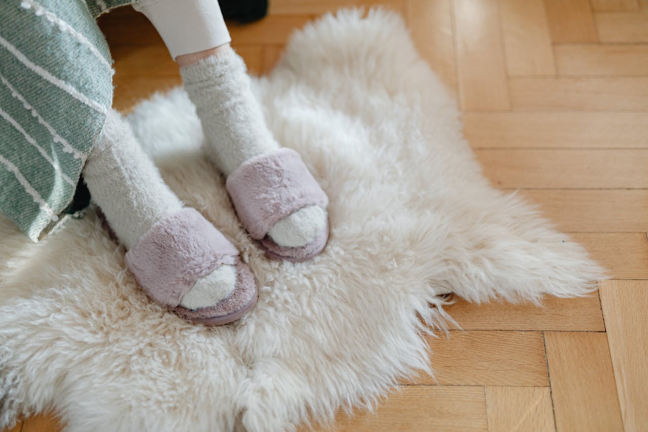 Warm and cozy feet in plush slippers resting on a soft fur rug for relaxation.